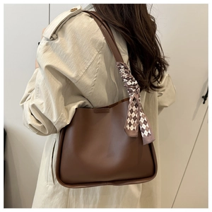 Detail of dark brown leather tote bag with a checkered silk scarf on the shoulder strap