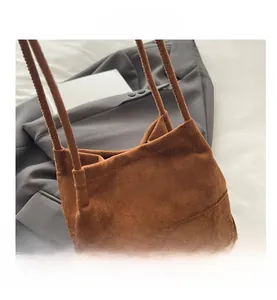 Détail du sac en daim marron à franges avec cordon de serrage et texture mate