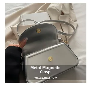 Nahaufnahme der silbernen Ledertasche mit goldenem Magnetverschluss und Klappendesign