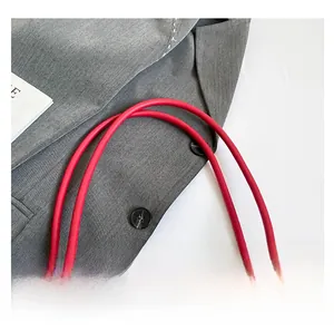 Detail of red leather handles and cream webbing strap with black printed letters