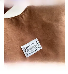 Detailed macro view of the brown suede tote bag with a minimalist polar bear logo tag