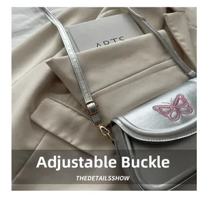 Details der silbernen Umhängetasche mit rosa Schmetterlingsstickerei und goldener Schnalle
