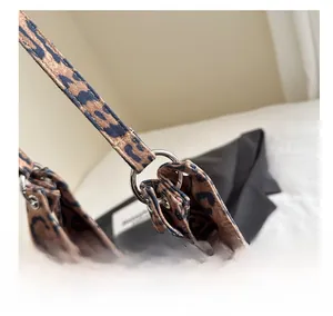 Detail shot of silver metal ring hardware and stitching on leopard tote bag strap