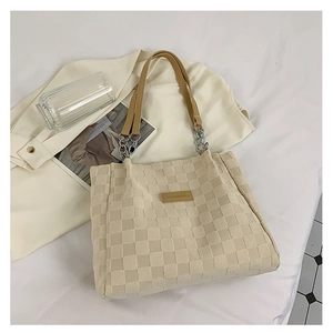 Detailed close-up of beige checkered tote bag with brown leather straps and metal chain