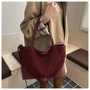 Detail of burgundy tote bag with knit fringe and bohemian tassels for winter style