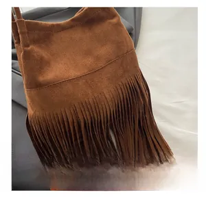 Gros plan des franges denses en daim caramel et de la finition de qualité sur le sac à main