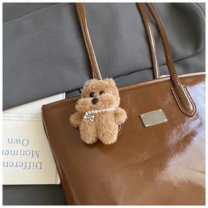 Gros plan d'un charm chien en peluche marron avec perles sur sac cabas en cuir