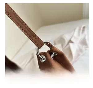 Macro view of silver metal buckle and fine stitching on brown suede tote bag