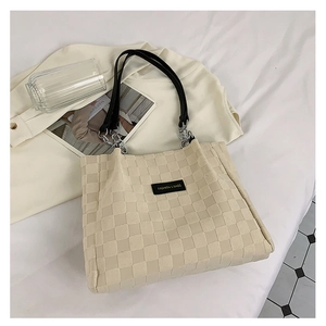 Detail of beige checkered tote bag featuring woven texture and fashion logo patch
