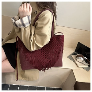 Detail of burgundy tote bag with woven fringes and leopard embossing in lifestyle setting