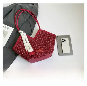 Detailed macro of red tweed tote bag with round leather handles and decorative white ribbon