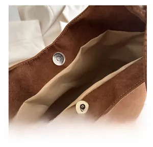 Close-up of high-quality magnetic metal buckle and soft suede lining on a brown shoulder bag
