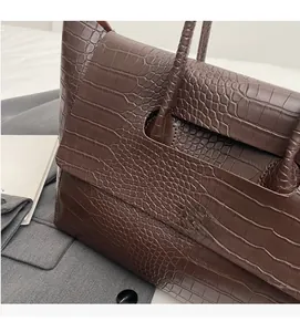 Dettaglio ravvicinato della borsa tote marrone scuro con trama a rilievo e manici solidi