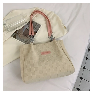 Close-up of beige woven tote bag with checkered texture and pink leather chain straps