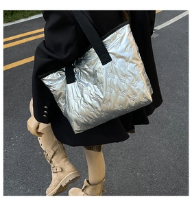 Close-up of metallic silver tote bag with quilted bow pattern and black shoulder strap
