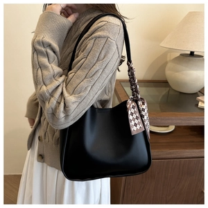 Detail of black faux leather tote bag featuring a decorative checkered silk scarf accent