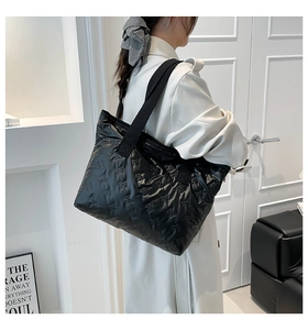 Close-up of black quilted tote bag featuring elegant bow relief patterns and shoulder strap