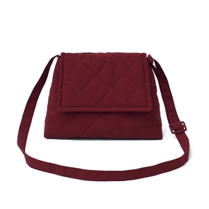 Front view of a burgundy quilted crossbody bag with diamond stitching and adjustable strap