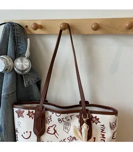 Detail of white canvas tote bag with brown leather trim and retro graffiti print patterns