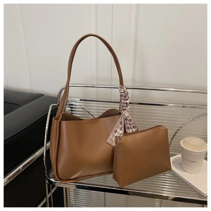 Close-up of brown leather tote bag with small pouch and decorative checkered scarf