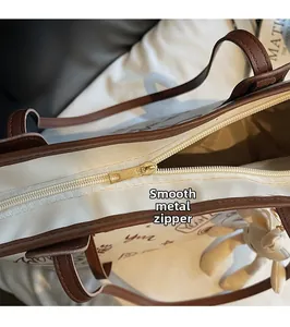 Detail of smooth metal zipper and brown PU leather trim on canvas tote bag