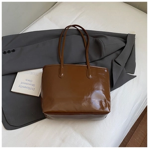 Détail du sac cabas marron caramel brillant avec coutures élégantes sur les poignées