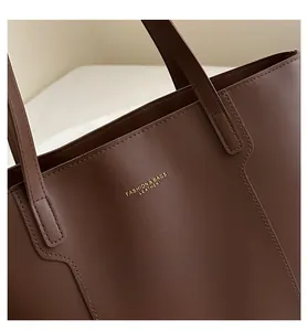 Detail of dark brown leather tote bag showing high-quality stitching and gold logo
