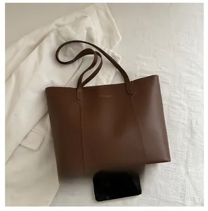 Size comparison of a dark brown large tote bag with a smartphone for scale