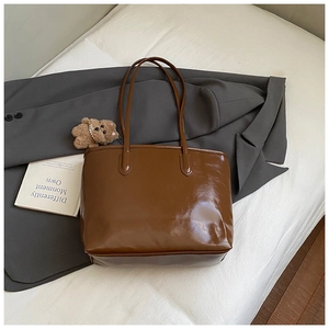 Détail d'un sac cabas marron foncé brillant avec un petit ours sur fond de style de vie