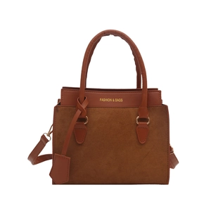 Brown contrast stitch handbag with suede finish and gold lettering on a white background