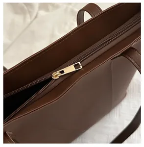 Detailed close-up of smooth gold zipper closure on high-quality dark brown tote bag
