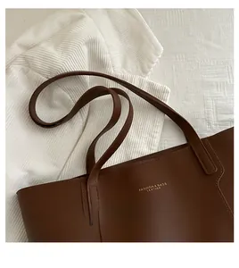 Detail of dark brown leather tote bag with gold logo text and premium texture finish