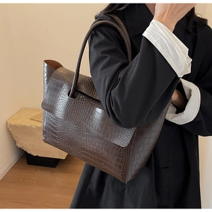 Dettaglio borsa shopper marrone scuro con trama a coccodrillo indossata da una modella