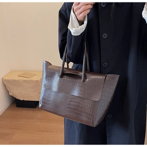 Dettaglio della borsa tote marrone scuro con stampa coccodrillo portata dalla modella