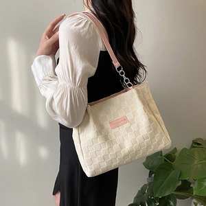 Off-white woven tote bag with pink straps and fashion label shown on model