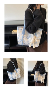 Detail of canvas tote bag featuring blue graffiti text and a cute plush bunny charm