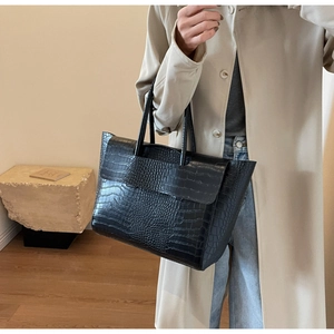 Dettaglio della trama coccodrillo nera su una borsa tote grande con chiusura a patta