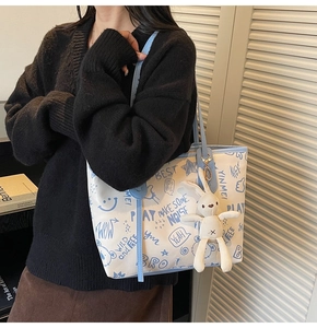 Detail of white tote bag with blue graffiti prints and cute rabbit plush pendant accessory