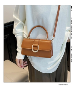 Close-up of retro brown shoulder bag with golden D-shaped buckle and leather texture