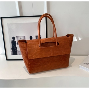 Dettaglio della borsa tote in pelle goffrata coccodrillo caramello con manici e patta