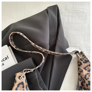 Gros plan sur la texture du sac léopard avec anneaux argentés sur un blazer noir