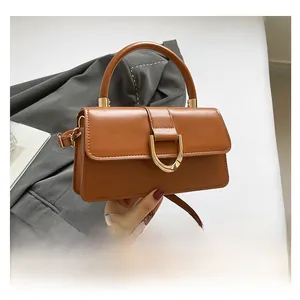 Detail of a brown PU leather handbag featuring a golden D-shaped buckle and top handle