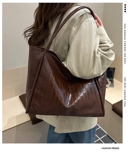 Detail of dark brown tote bag with crocodile pattern and dual slim shoulder straps