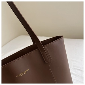 Detail of dark brown leather tote bag with gold lettering and precise stitching details