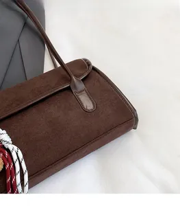Detail view of deep brown suede shoulder bag with woven rope accent and leather trim