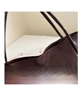 Close-up detail of dark brown crocodile embossed leather texture on large tote bag