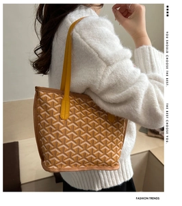 Side view of a yellow tote bag featuring a classic Y-pattern and long leather straps