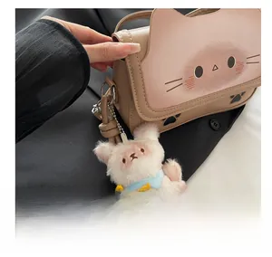 Detail showing brown leather cat shoulder bag with a fluffy white plush animal pendant