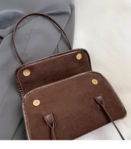 Detail of four golden magnetic clasps on a brown suede and leather handbag interior