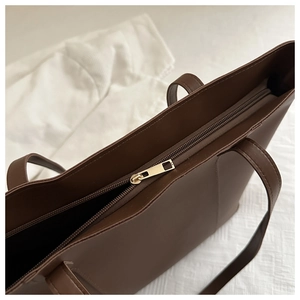 Detailed close-up of high-quality brown tote bag with premium golden metal zipper closure
